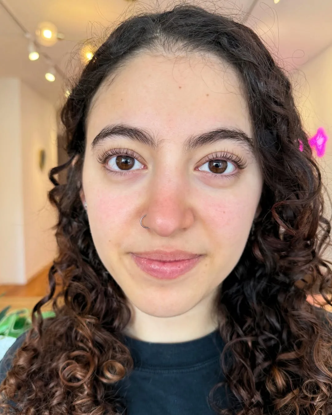 Client with curly dark hair and a subtle natural lash set in the studio
